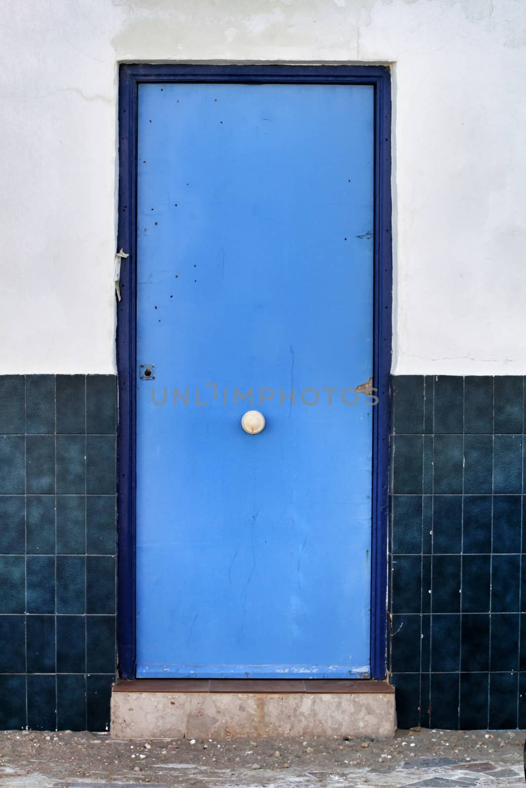 Blue door and white and blue tiled facade in Alicante, Spain.