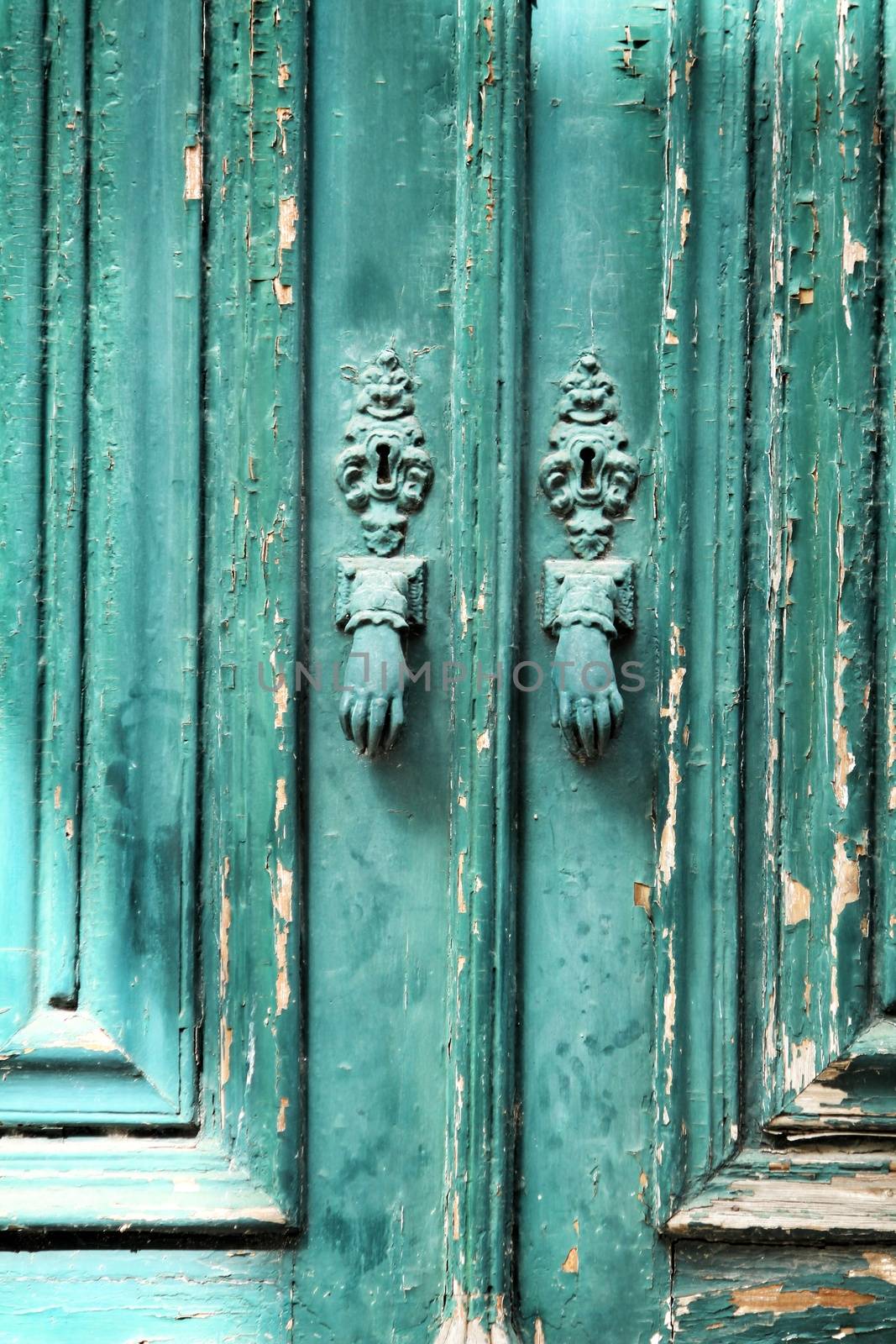 Door knockers with hand shape on green wooden door by soniabonet