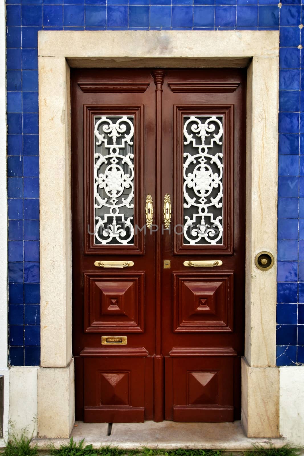 Old and colorful wooden door with iron details and blue tiled facade in Lisbon, Portugal