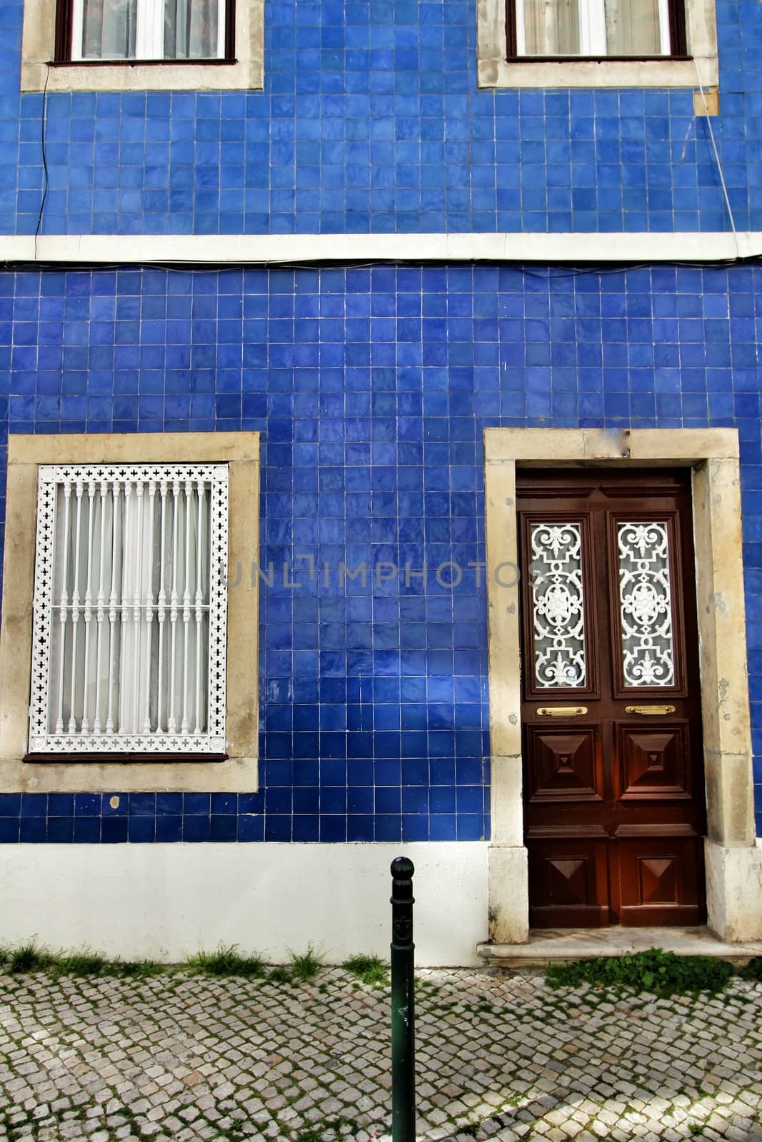 Old and colorful wooden door with iron details and blue tiled facade in Lisbon, Portugal