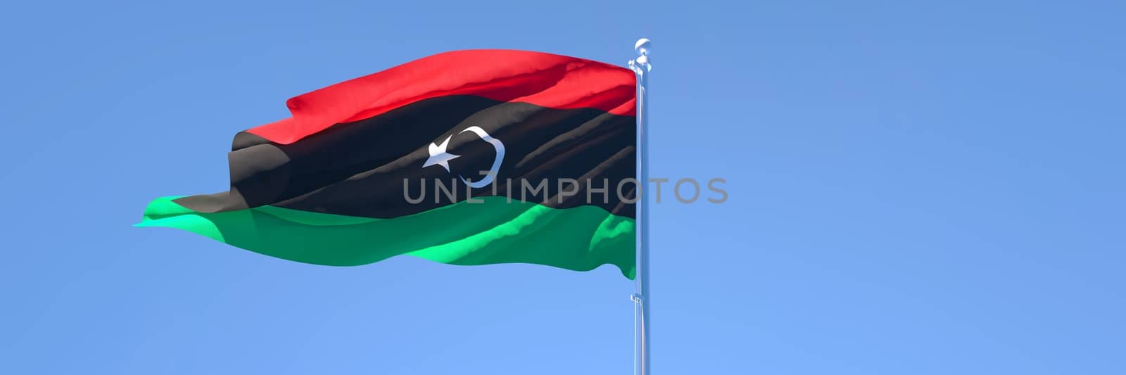 3D rendering of the national flag of Libya waving in the wind against a blue sky.