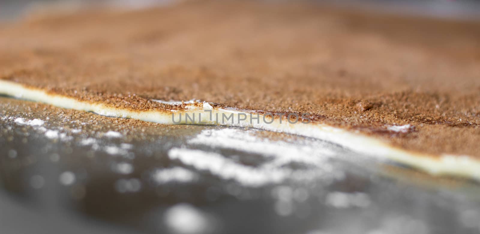 Rolled pastry sprinkled with sugar and cinnamon for baking buns. I cook buns at home in the oven.