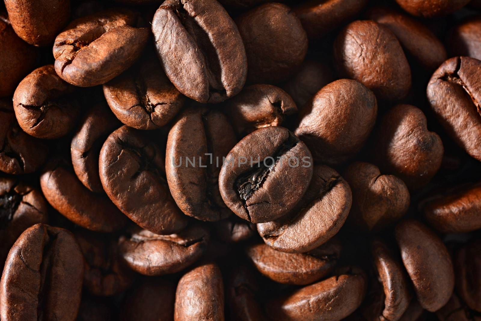 Roasted coffee beans full frame background. Macro shot of coffee beans with visible texture.