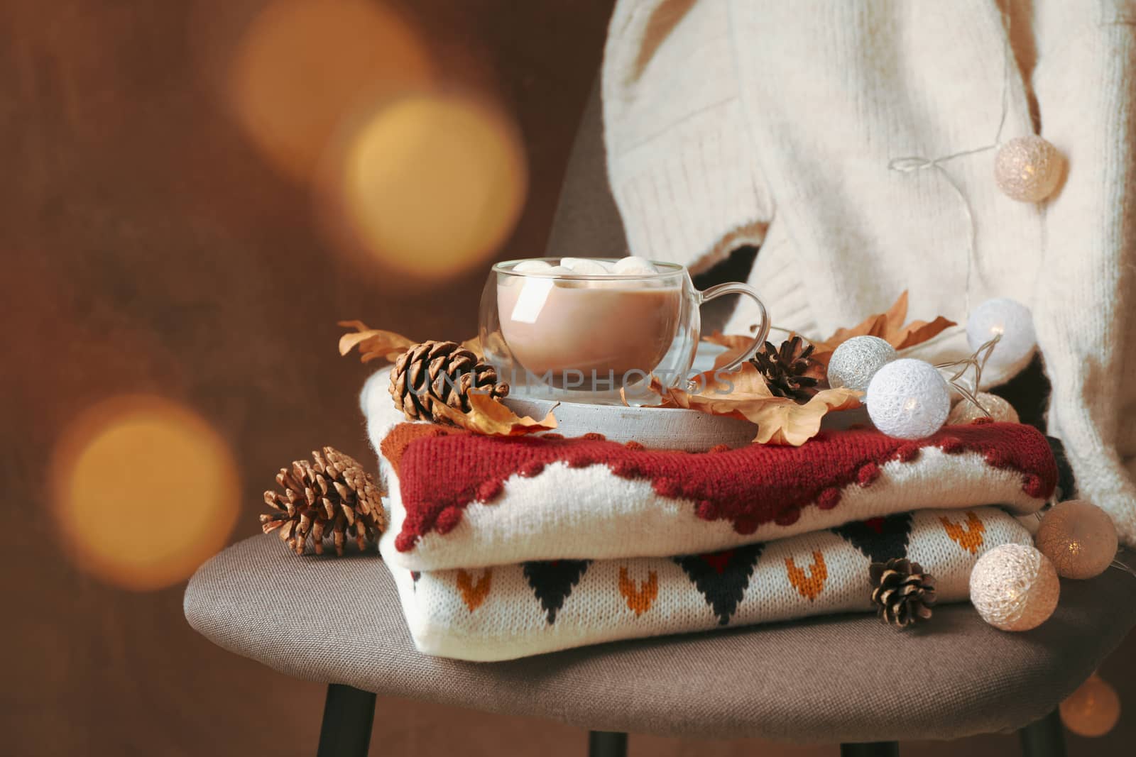 Autumn concept with sweaters, cup of coffee and blurred lights by AtlasCompany