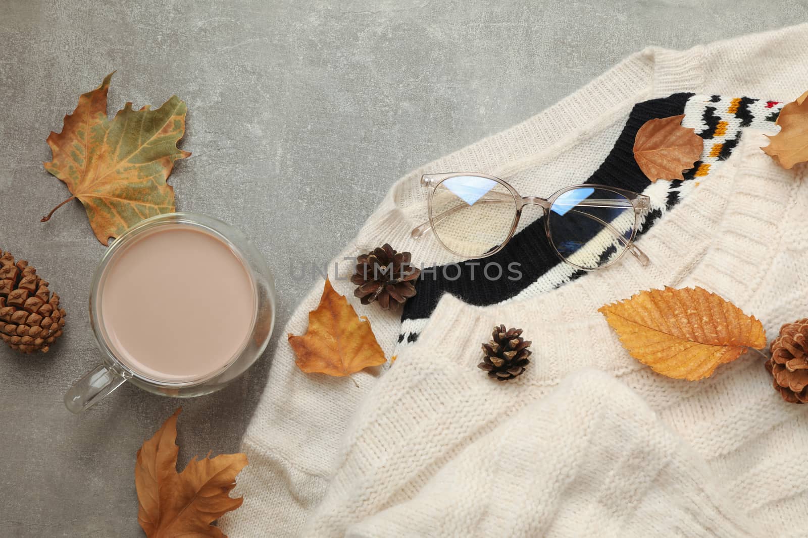 Concept of autumn wear with sweaters and coffee on gray background