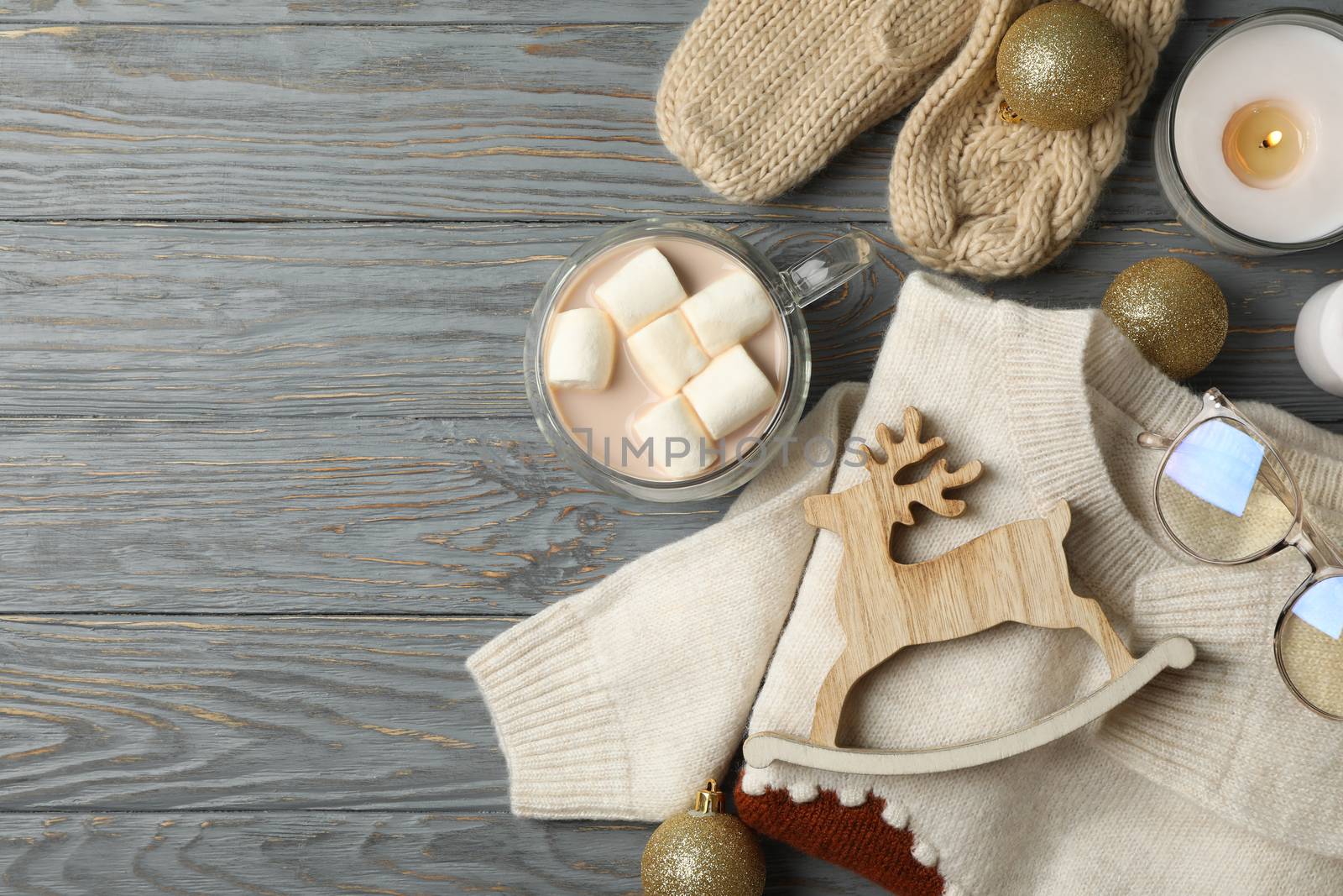 Winter concept with coffee with marshmallow, sweater and candles on wooden background