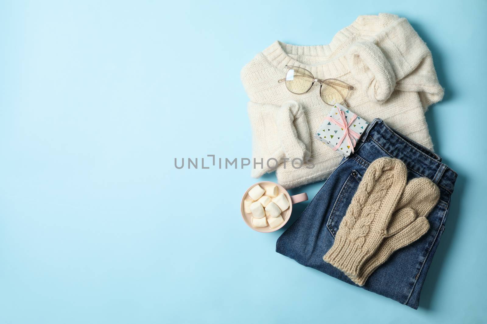 Winter concept with sweater and gift box on blue background by AtlasCompany