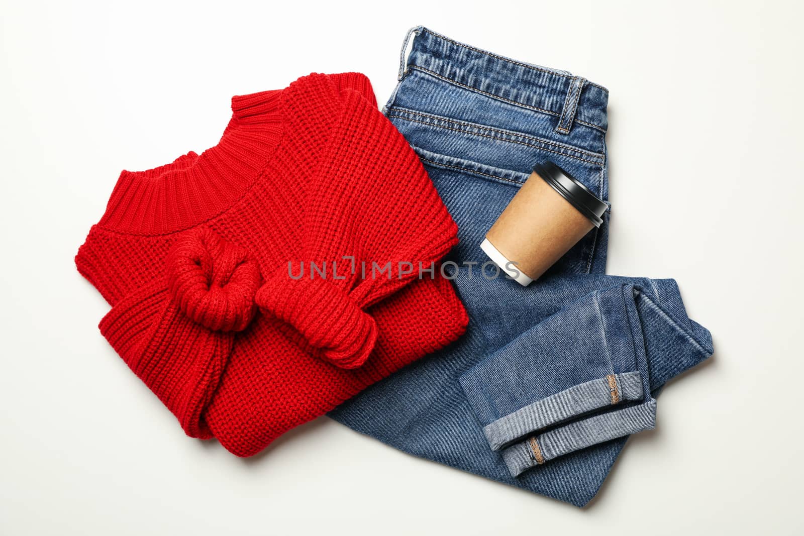 Sweater, jeans and paper cup on white background