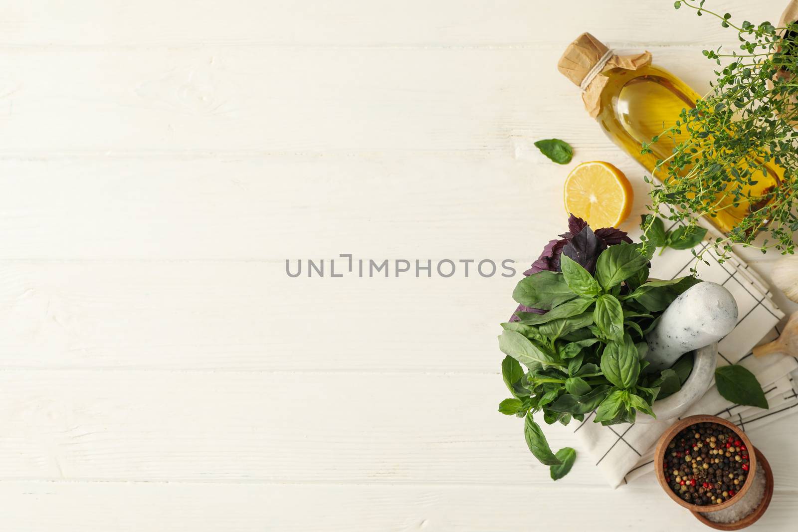 Different herbs, oil and spices on white wooden background