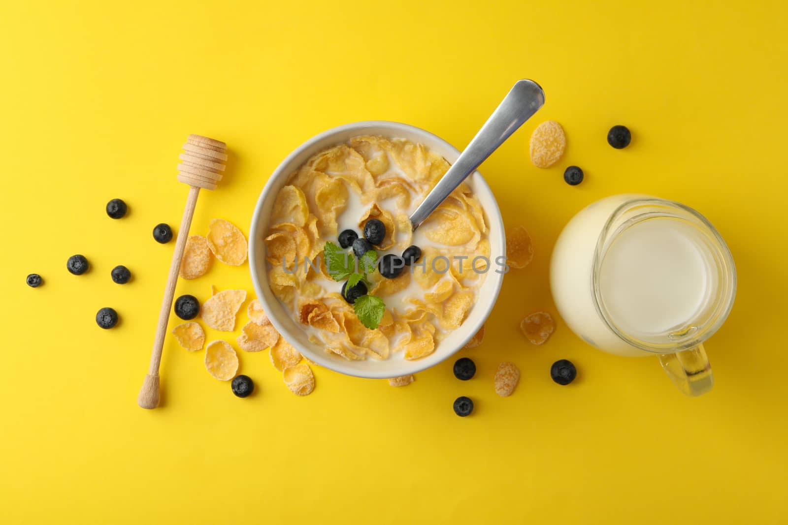 Milk, bowl of muesli and dipper on yellow background