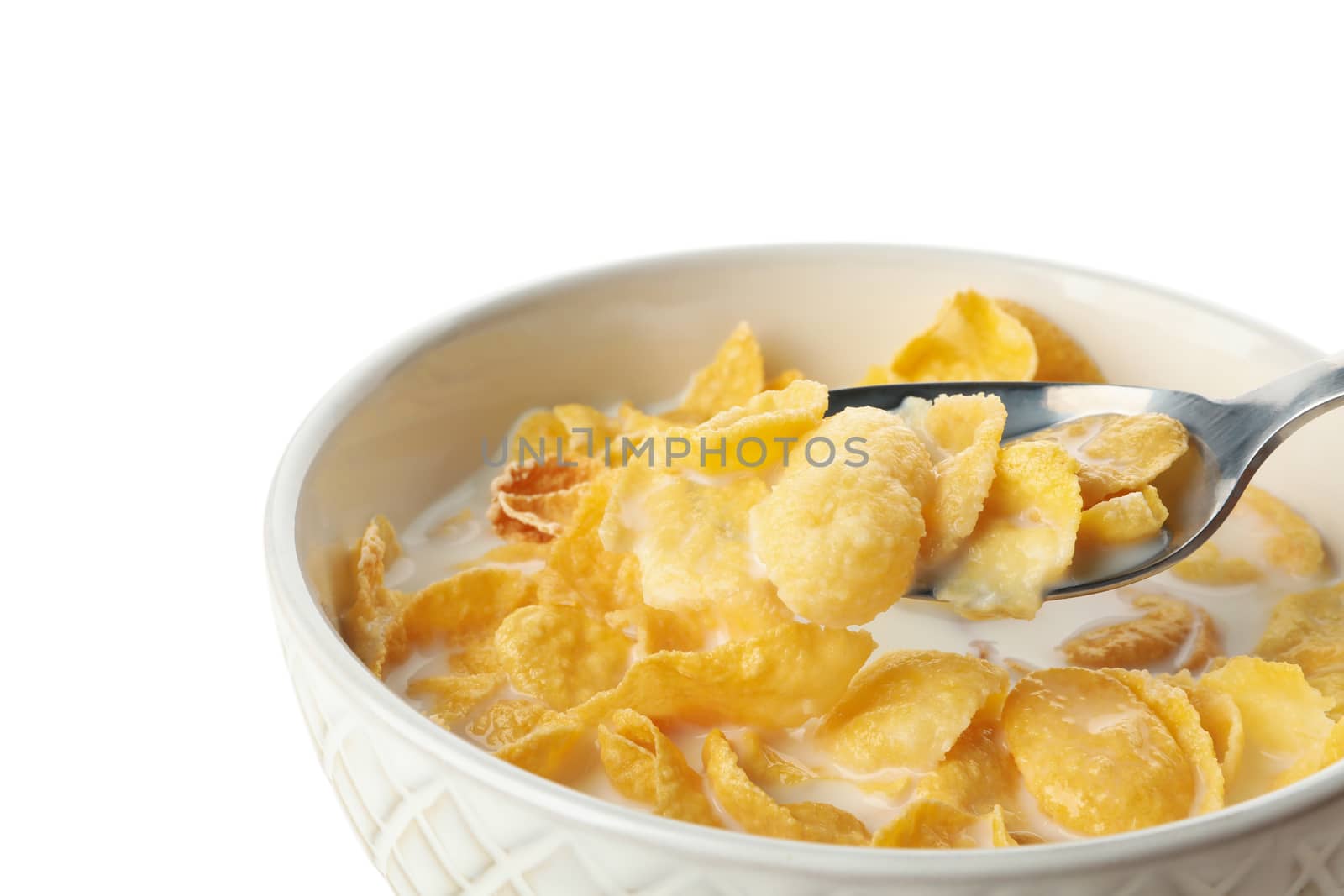 Spoon and bowl of muesli with milk isolated on white background