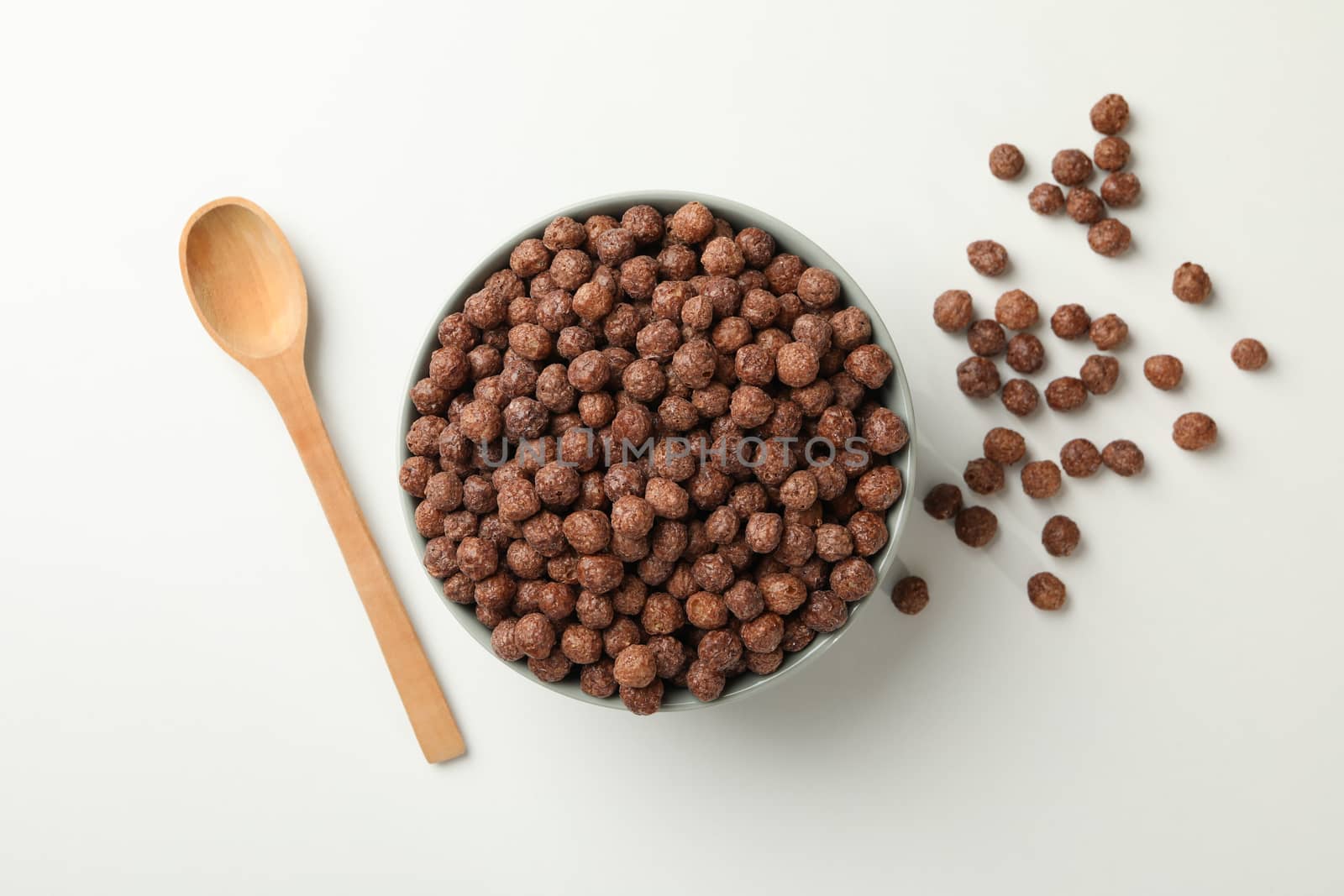 Spoon and bowl with corn balls on white background, top view