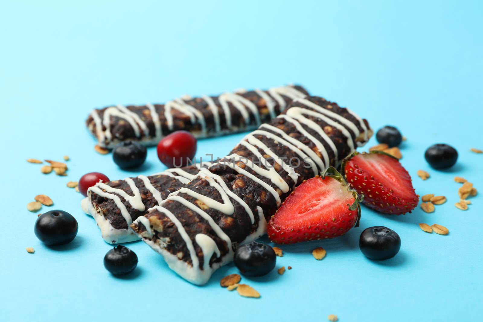 Tasty granola bars on blue background, close up