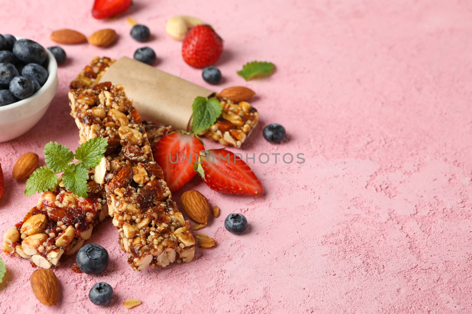 Granola bars and bowl with blueberry on pink background, space for text