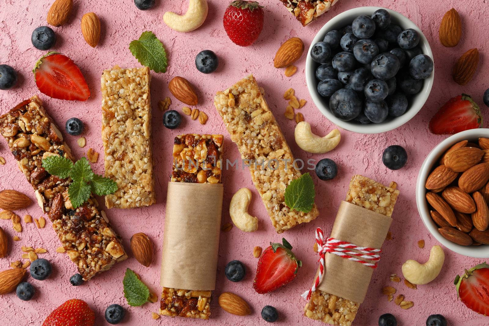 Granola bars and bowl with blueberry on pink background, top view