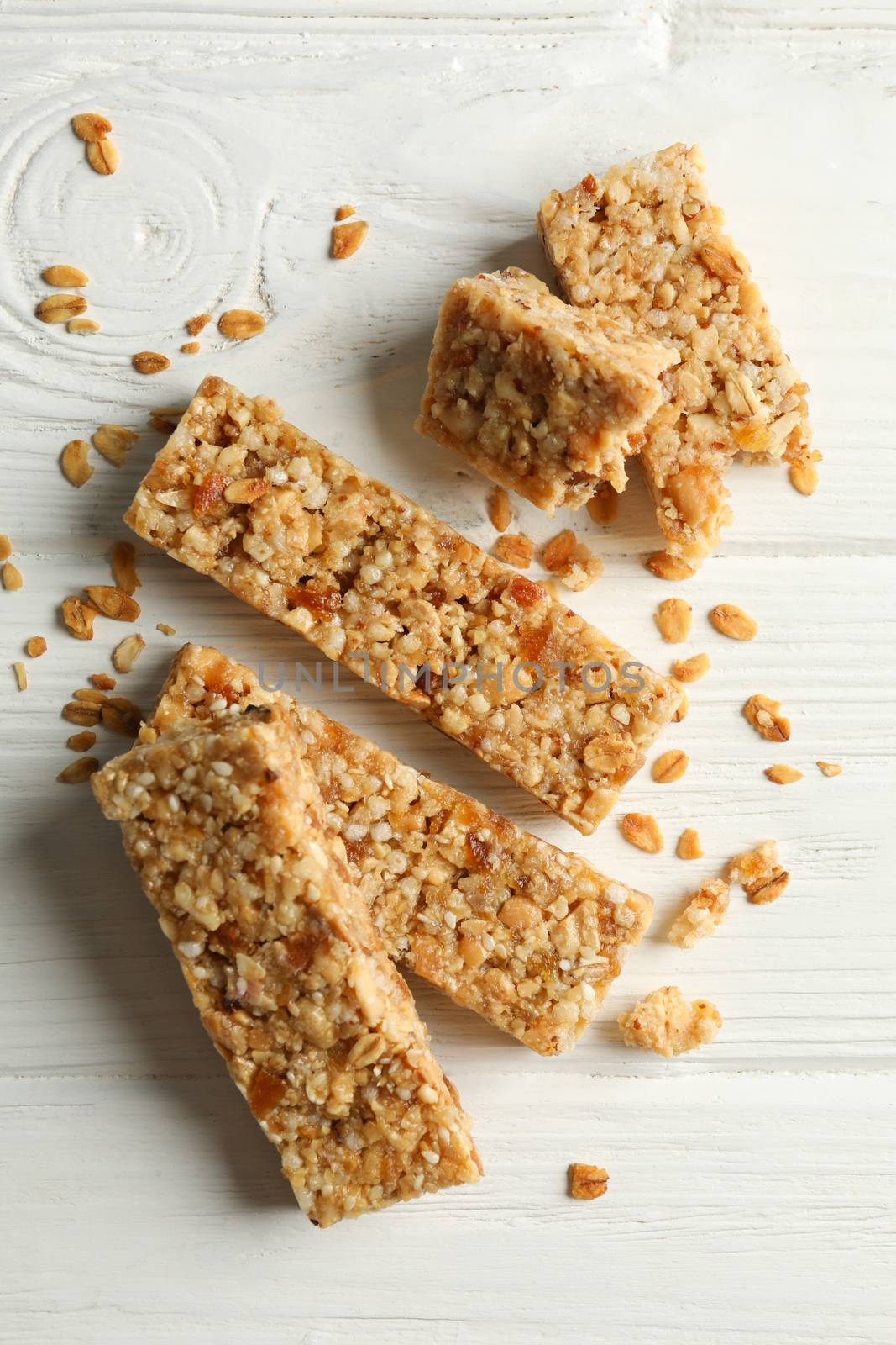 Tasty granola bars on white wooden background