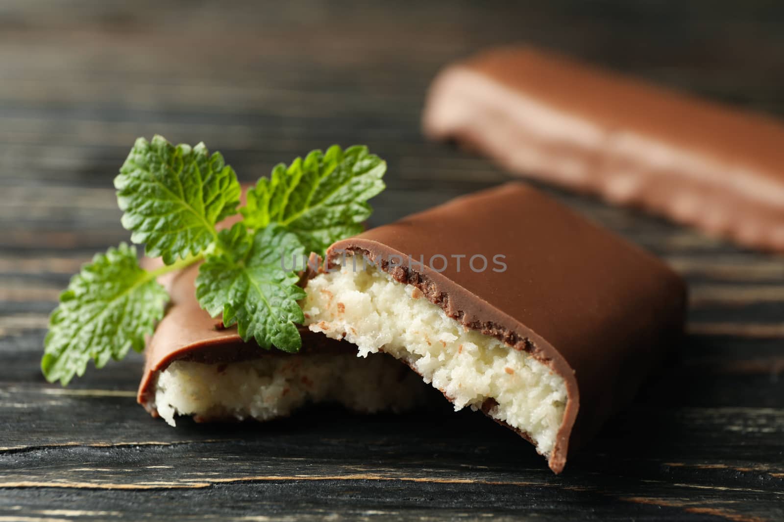 Mint and coconut bars in chocolate on wooden background