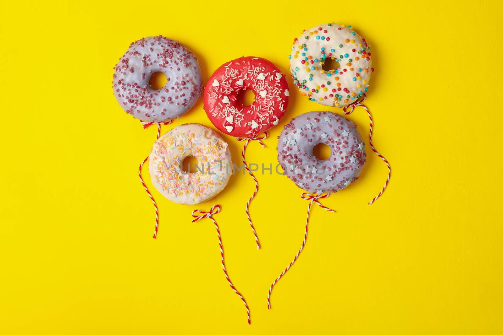 Concept of balloons made of donuts on yellow background