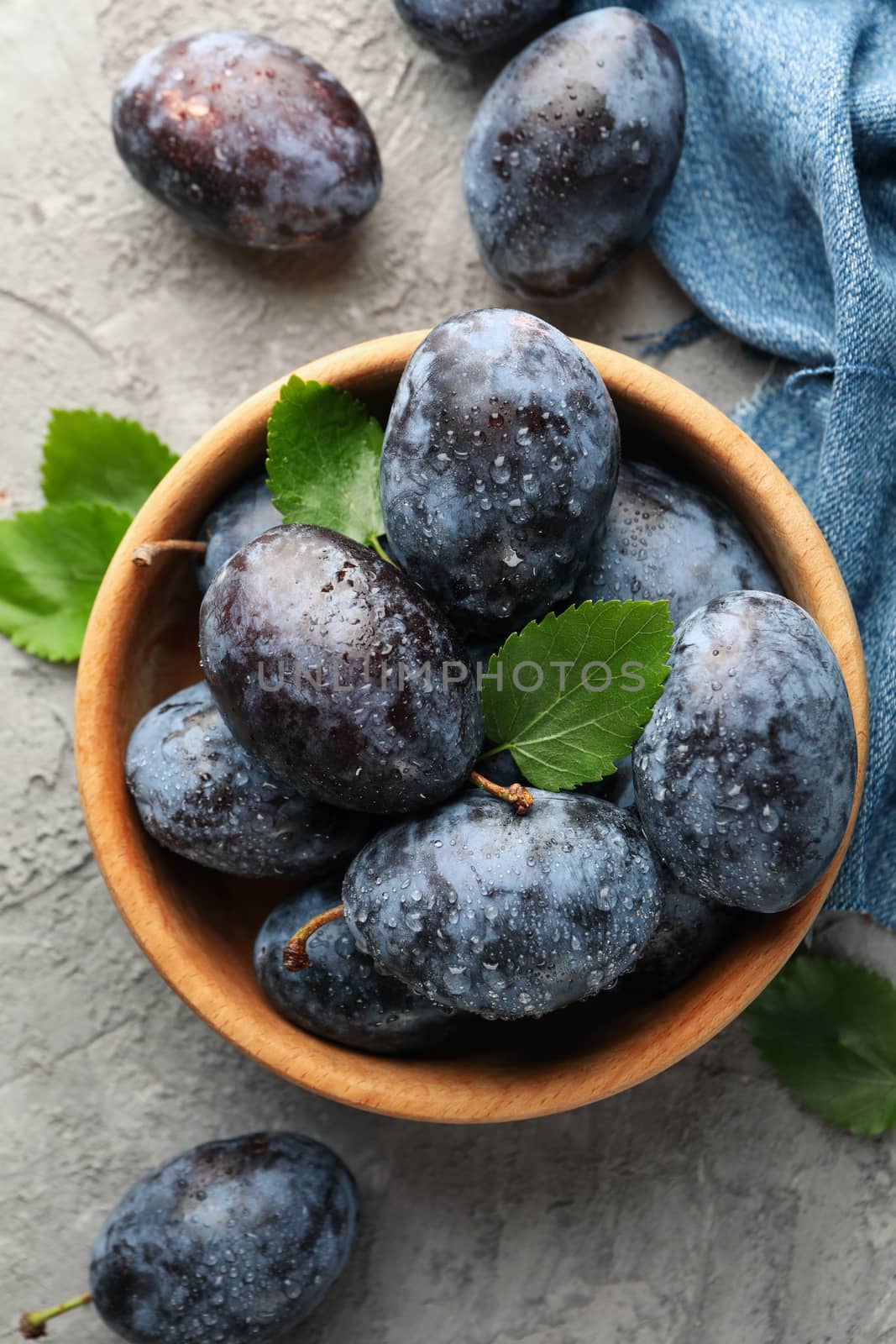 Napkin and bowl with plums on gray background by AtlasCompany
