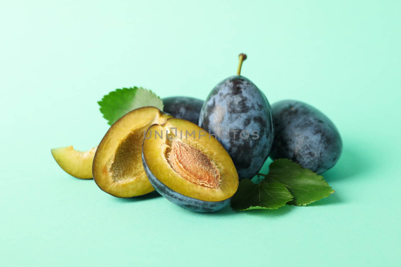 Fresh plums and leaves on mint background