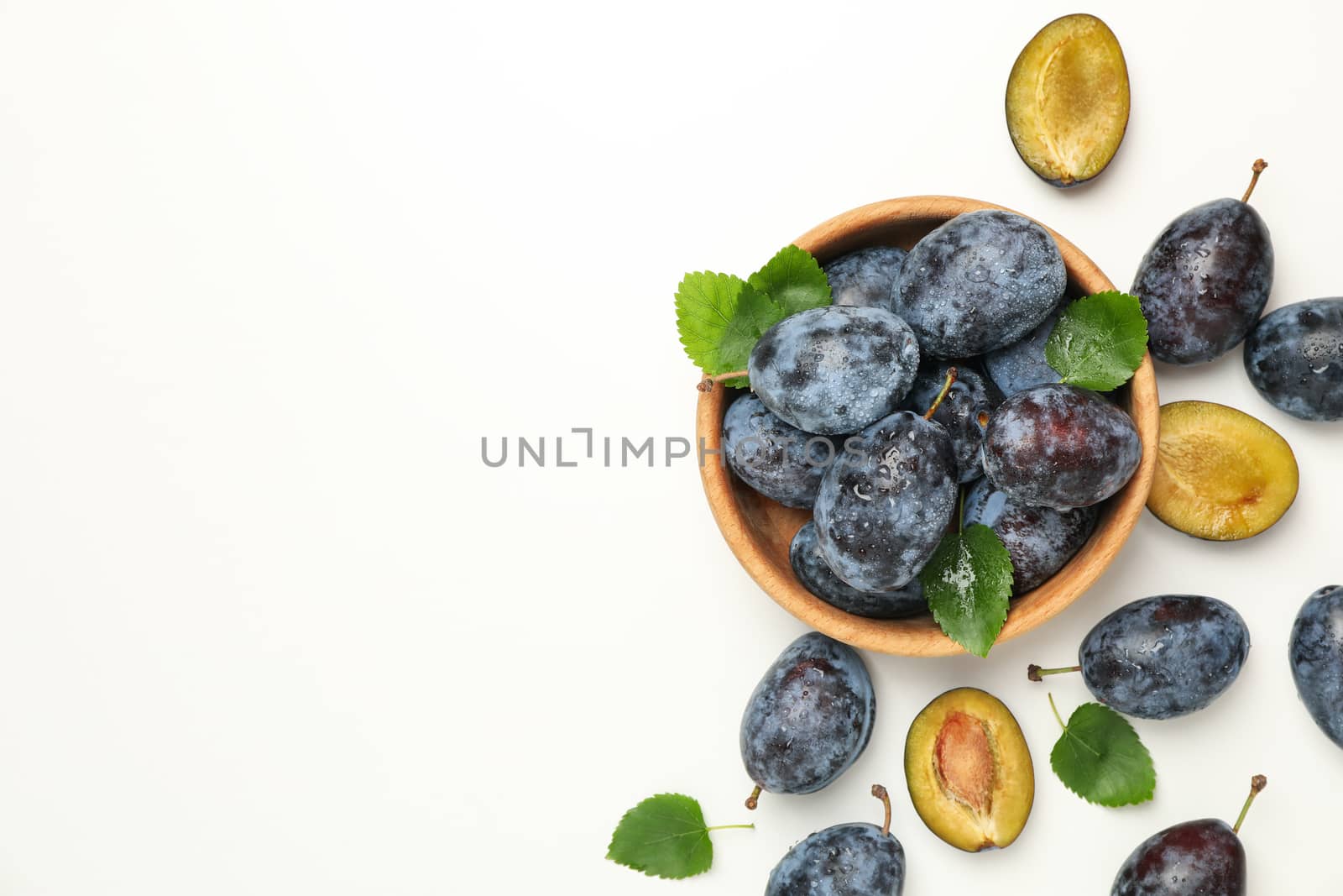 Bowl with fresh plums on white background, top view