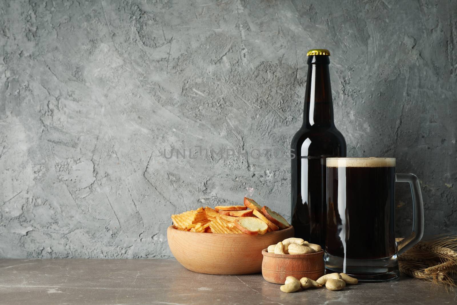 Beer, wheat and snacks on gray background