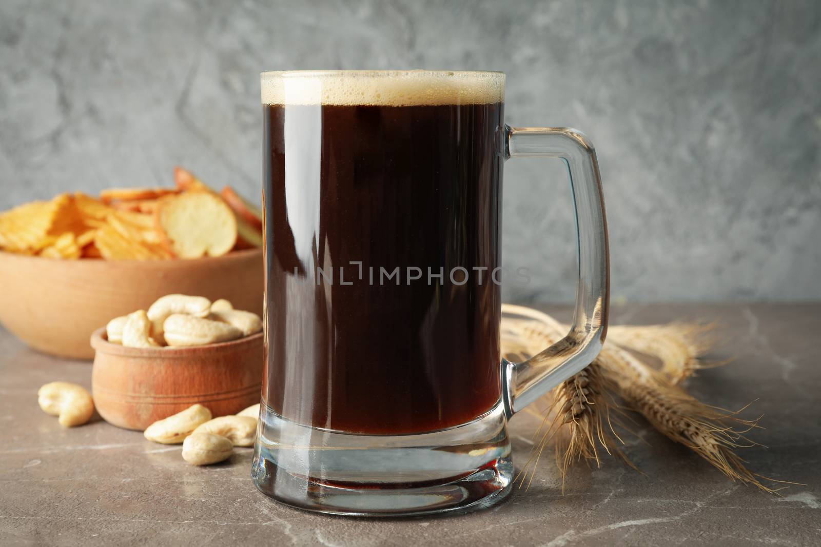 Beer, wheat and snacks on gray background, close up