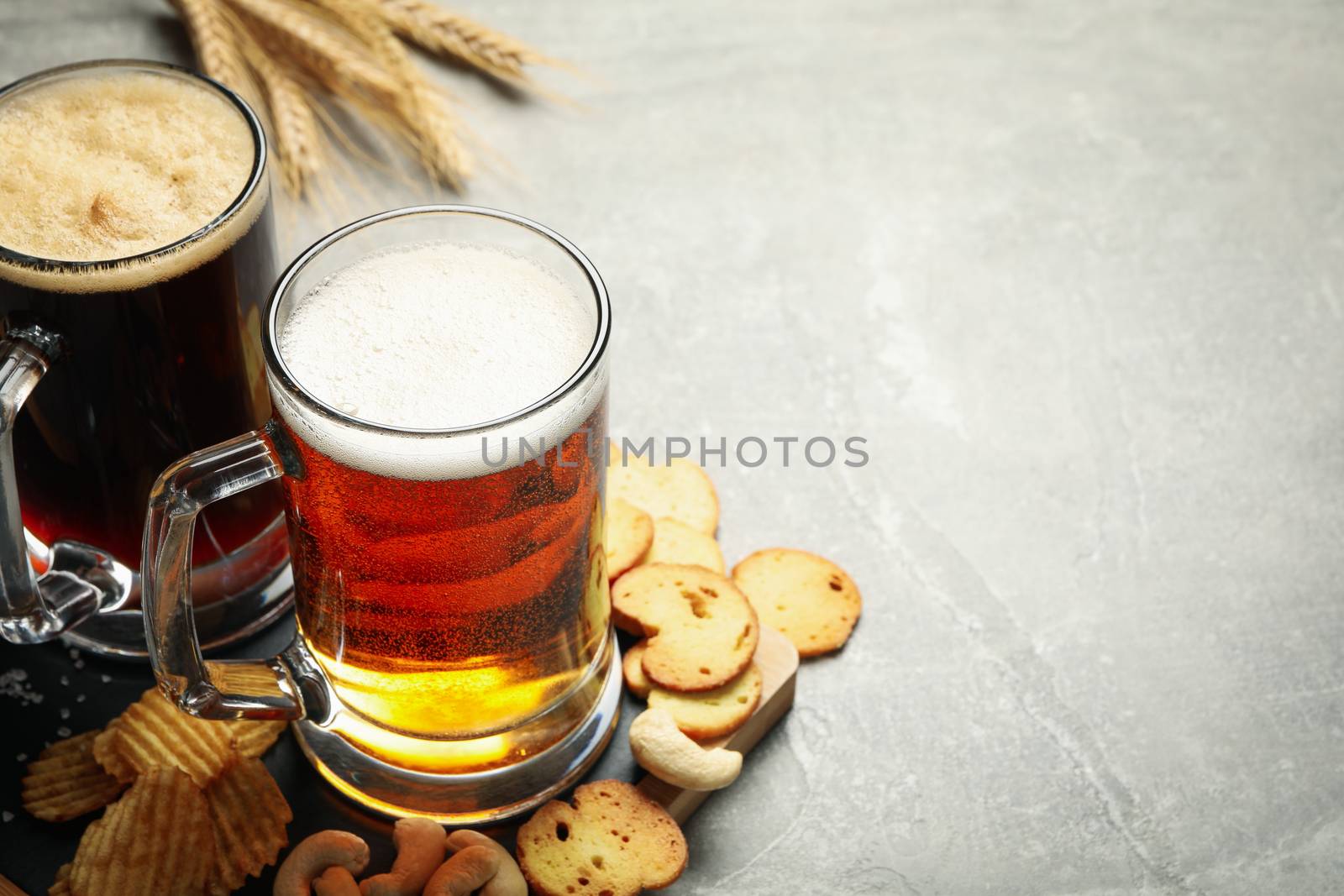 Beer, wheat and snacks on gray background