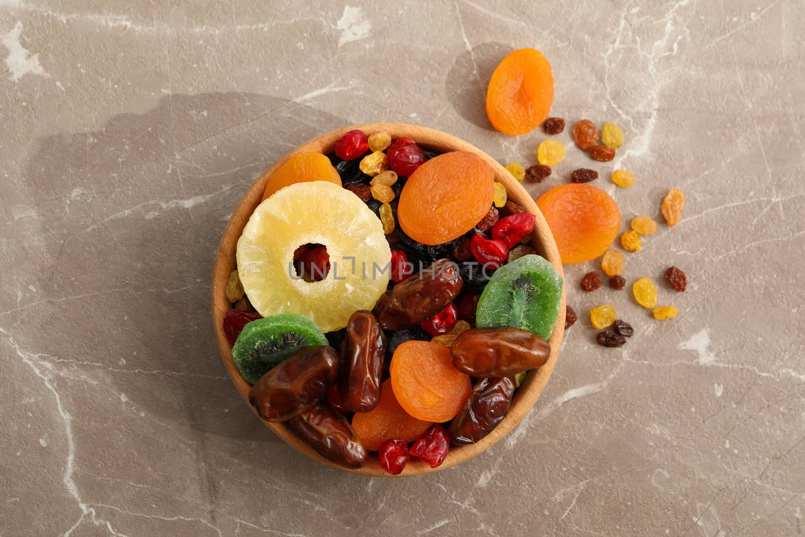 Wooden bowl with dried fruits on gray background