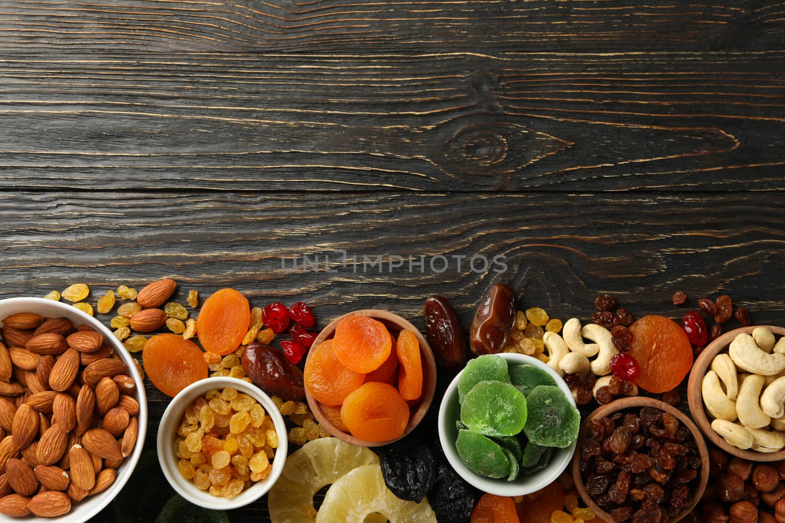 Bowls with dried fruits and nuts on wooden background by AtlasCompany