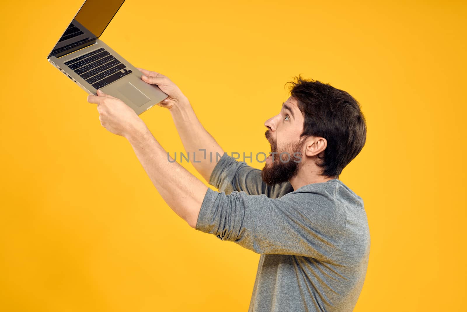 man with laptop wireless technology internet lifestyle work yellow isolated background. High quality photo