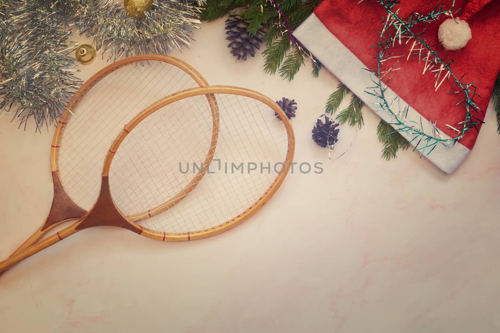 Badminton rackets and Christmas decorations on a light background. Greeting card with the concept of a healthy lifestyle. Top view with copy space. Flat lay
