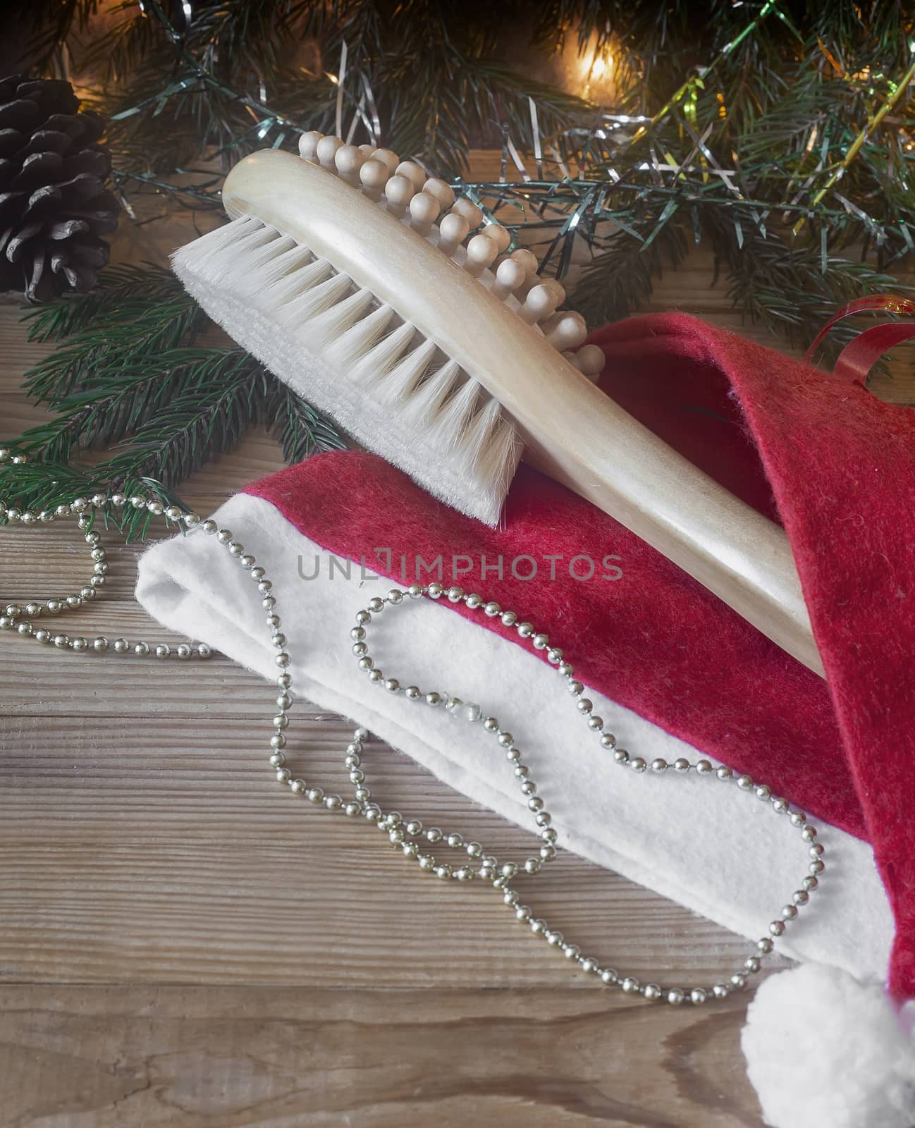 Wooden Spa massage brush and Christmas decorations: Christmas tree, garlands, cones on a wooden background, Christmas Wellness concept