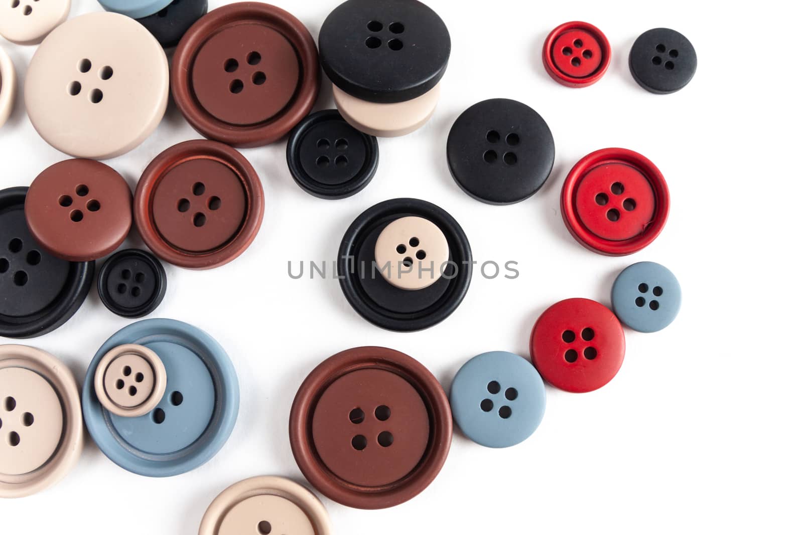 Pile of color brown, beige, grey, red, black plastic matte buttons on white, beautiful needlework, minimalism. Use for sewing. Space for text.