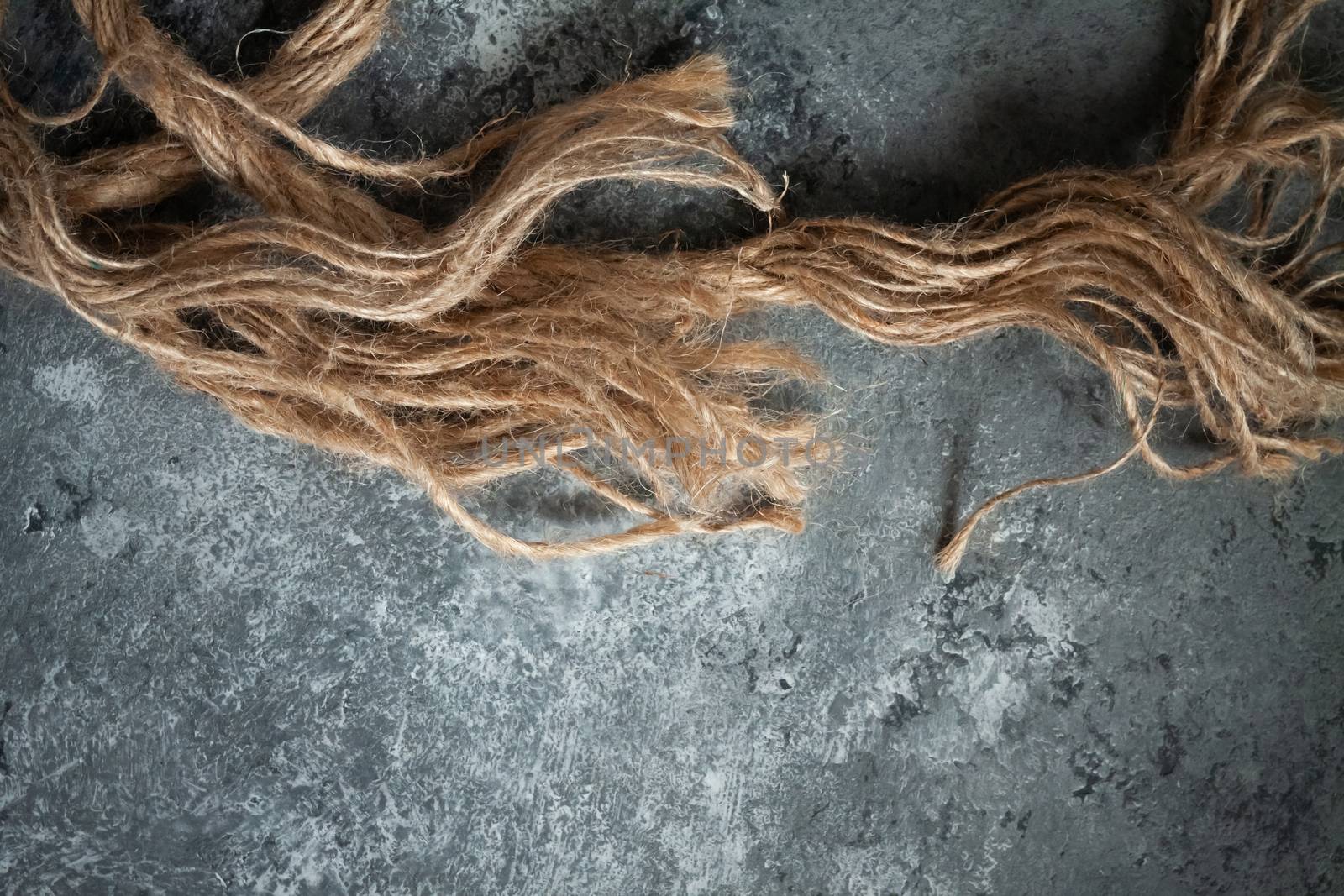 large battered jute rope on a gray abstract concrete background. Space for text.