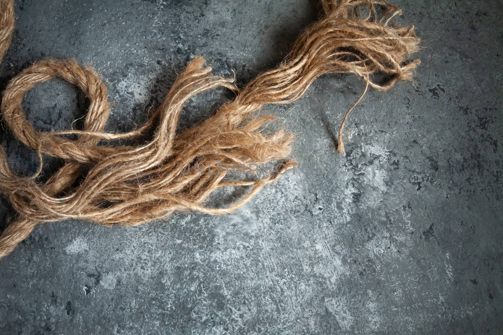 large battered jute rope on a gray abstract concrete background. Space for text.