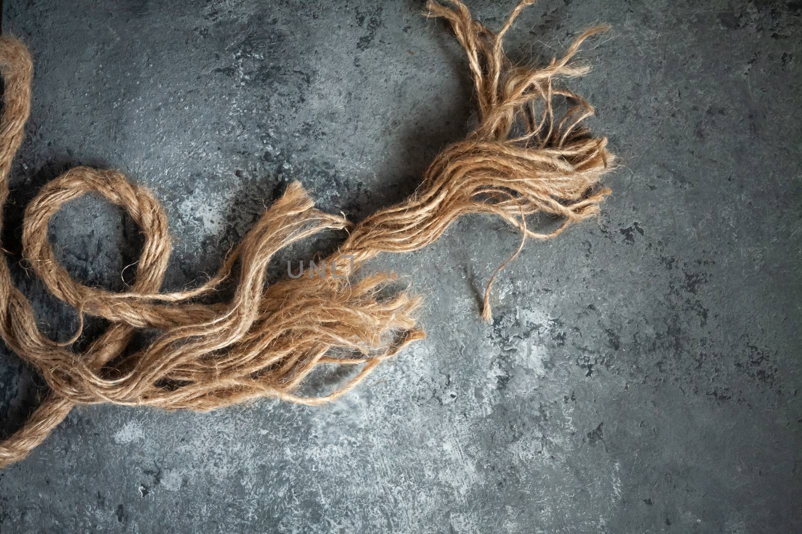 large battered jute rope on a gray abstract concrete background. Space for text.