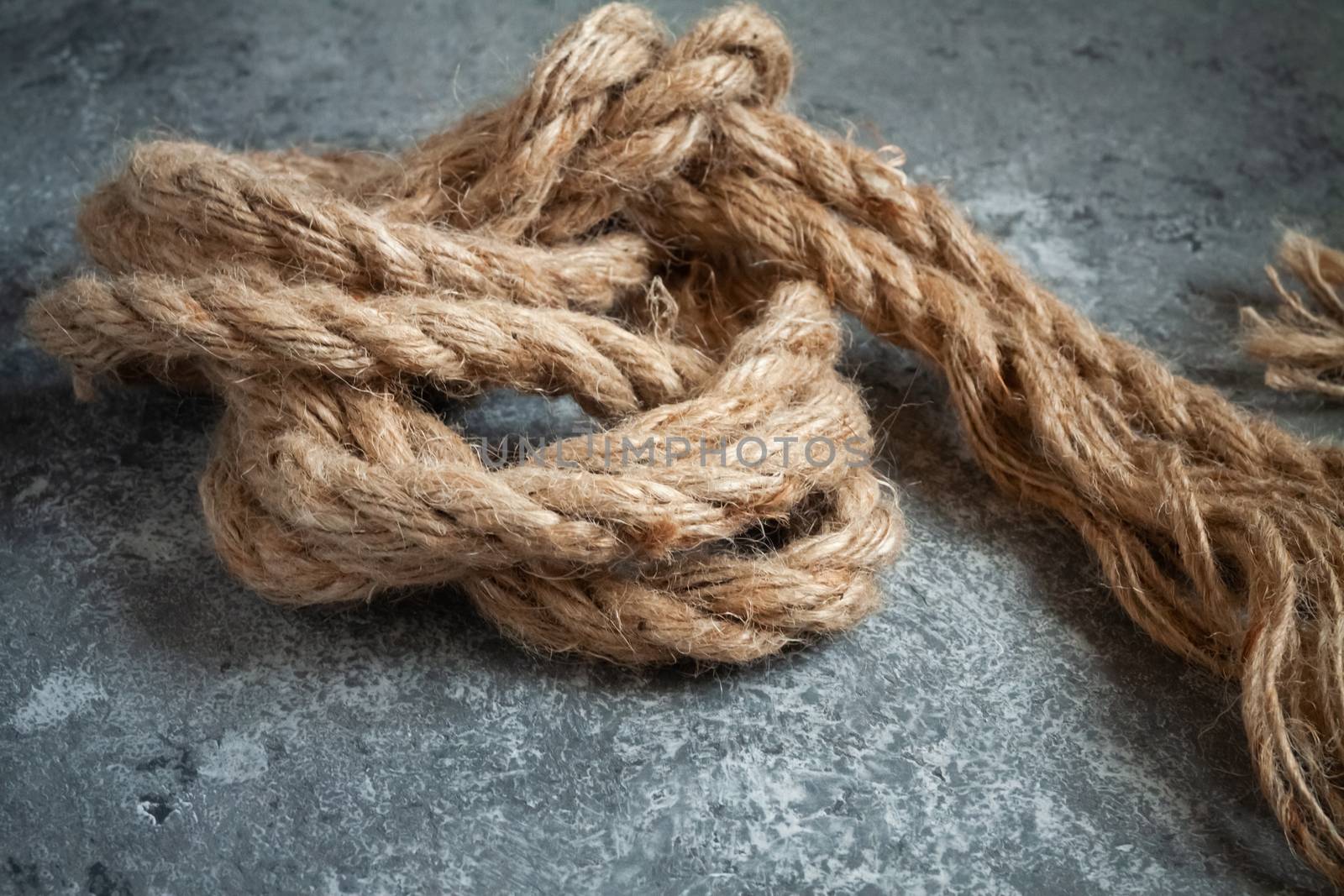 large battered jute rope on a gray abstract concrete background. Space for text.