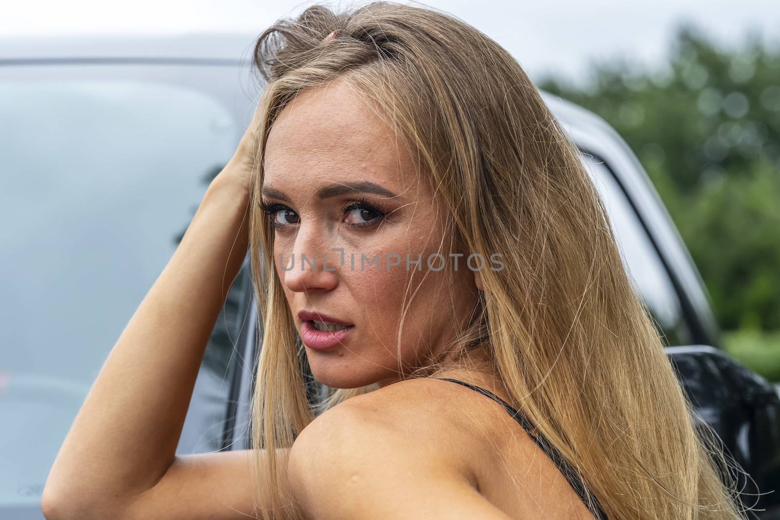 A gorgeous blonde model poses with a black truck on a fall day