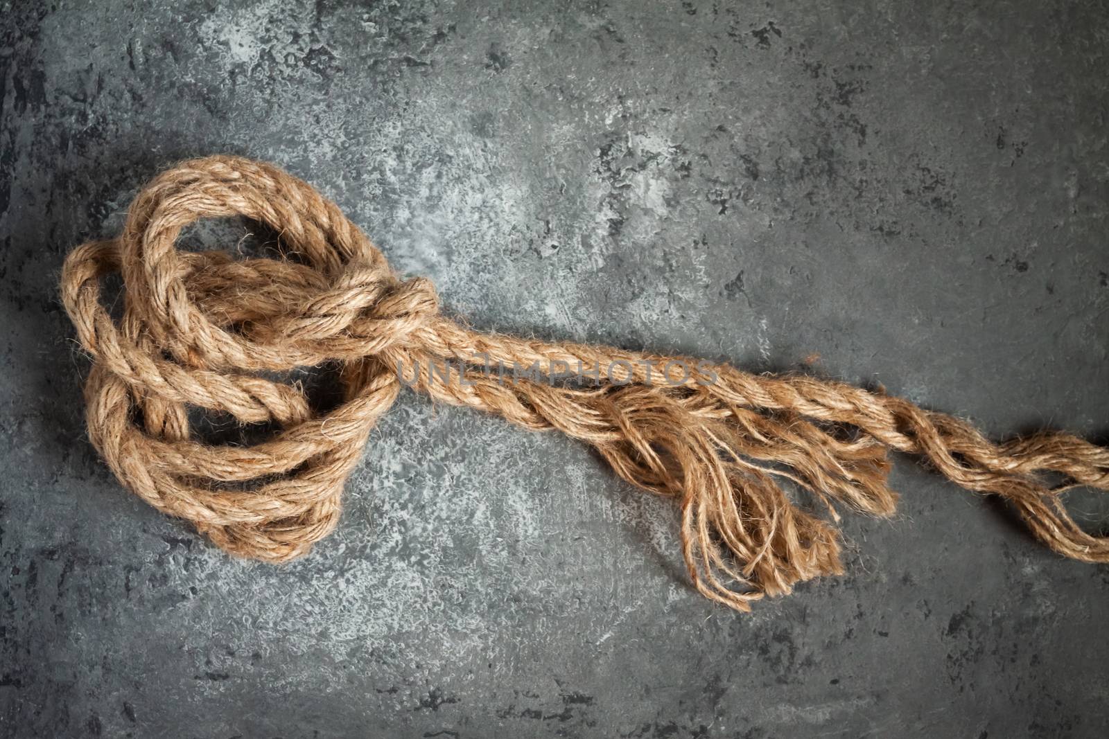 large battered jute rope on a gray abstract concrete background. Space for text.