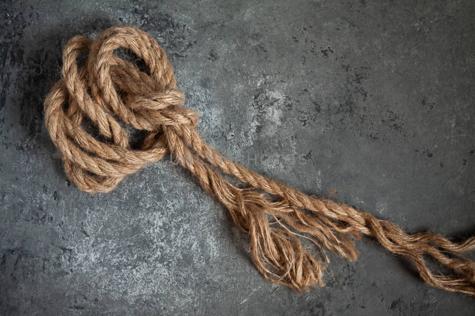 large battered jute rope on a gray abstract concrete background. Space for text.