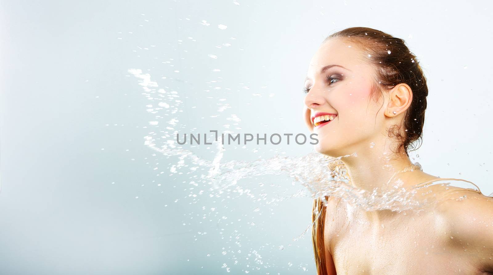 pretty woman with water splash. Beautiful model woman with a splash of water. Beautiful smiling girl underwater with fresh skin on blue background. Skin care, cleansing and moisturizing concept. Pretty face