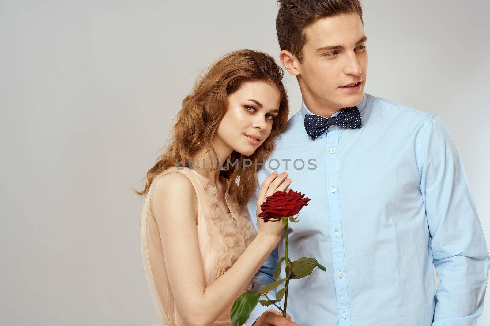 A loving young couple with a red rose in their hands on a light background romance by SHOTPRIME
