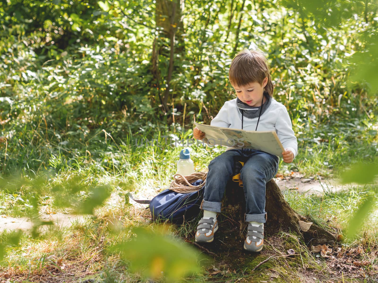 Little explorer on hike in forest. Boy with binoculars, backpack by aksenovko