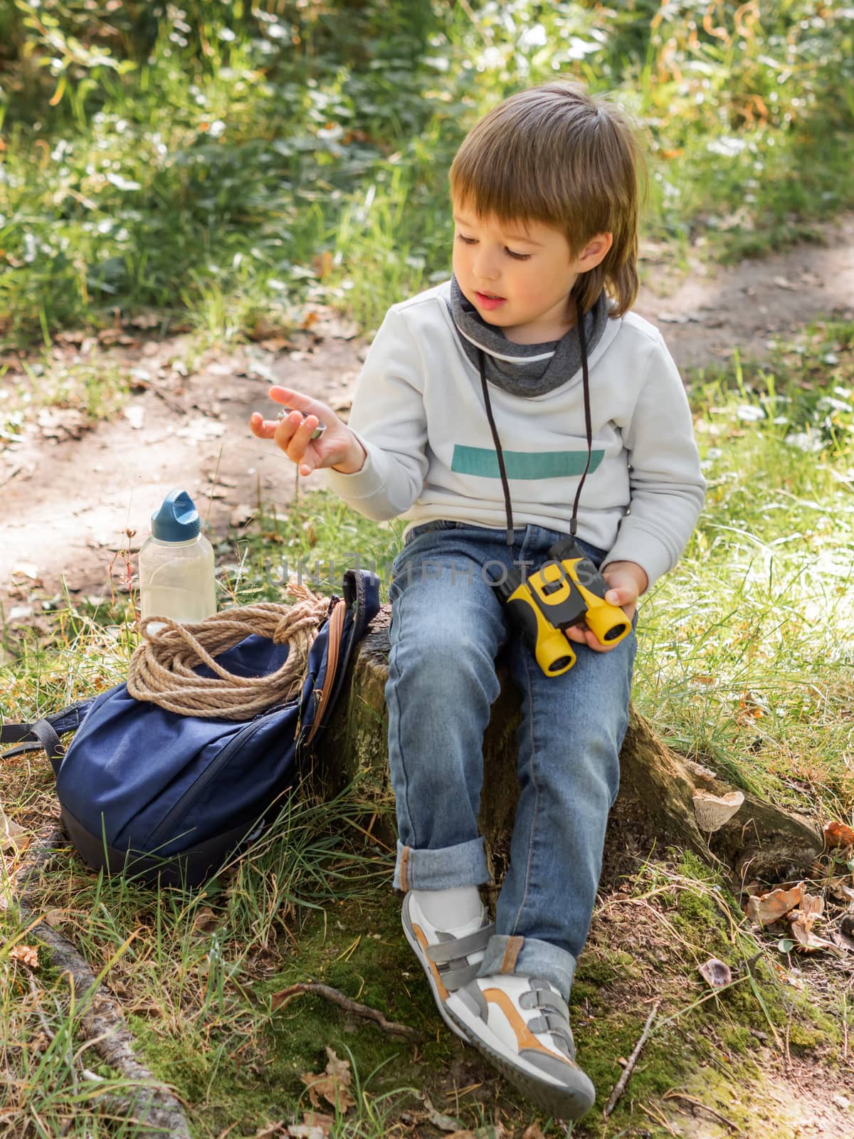 Little explorer on hike in forest. Boy with binoculars and compa by aksenovko