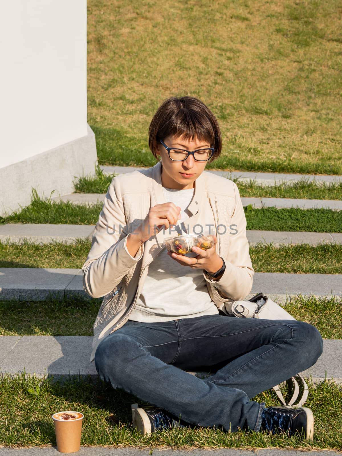 Woman sits on park bench with take away lunch box, cardboard cup by aksenovko