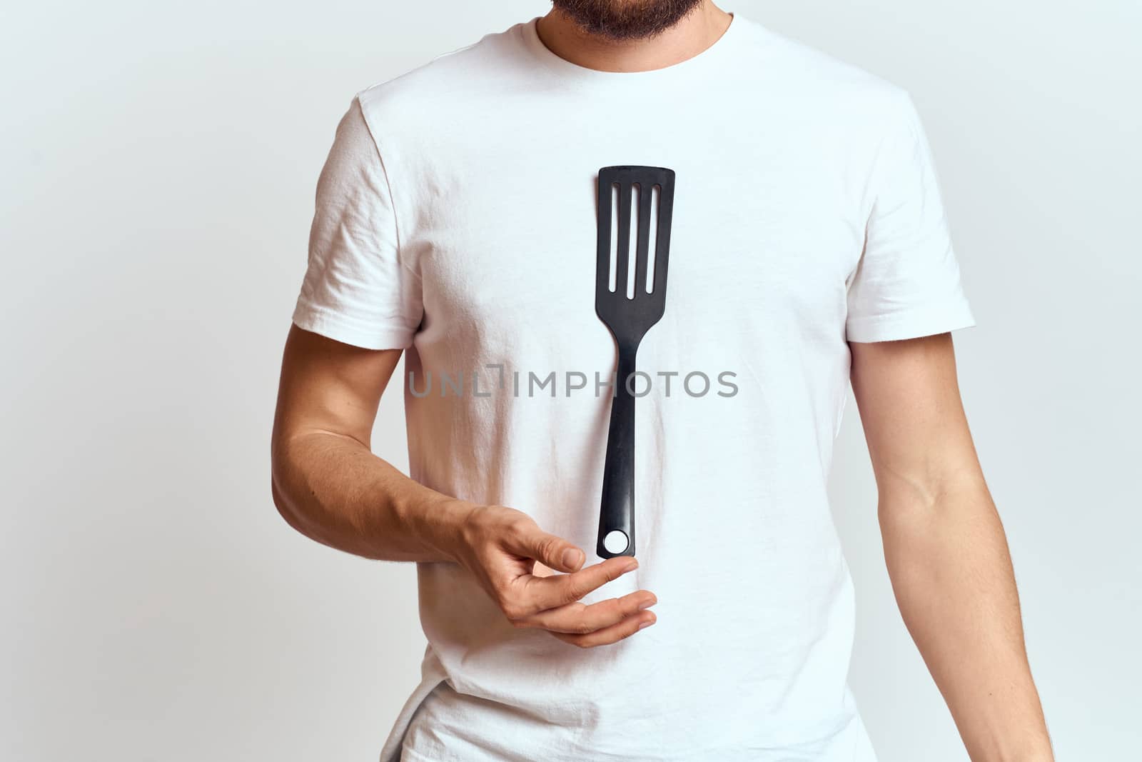 man with shovel for cooking white t-shirt cropped view light background. High quality photo