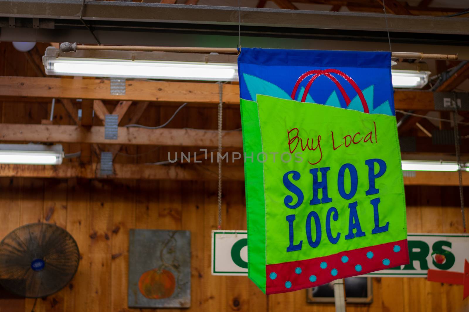 A Hanging Sign in a Wooden Farmer's Market That Says Buy Local Shop Local
