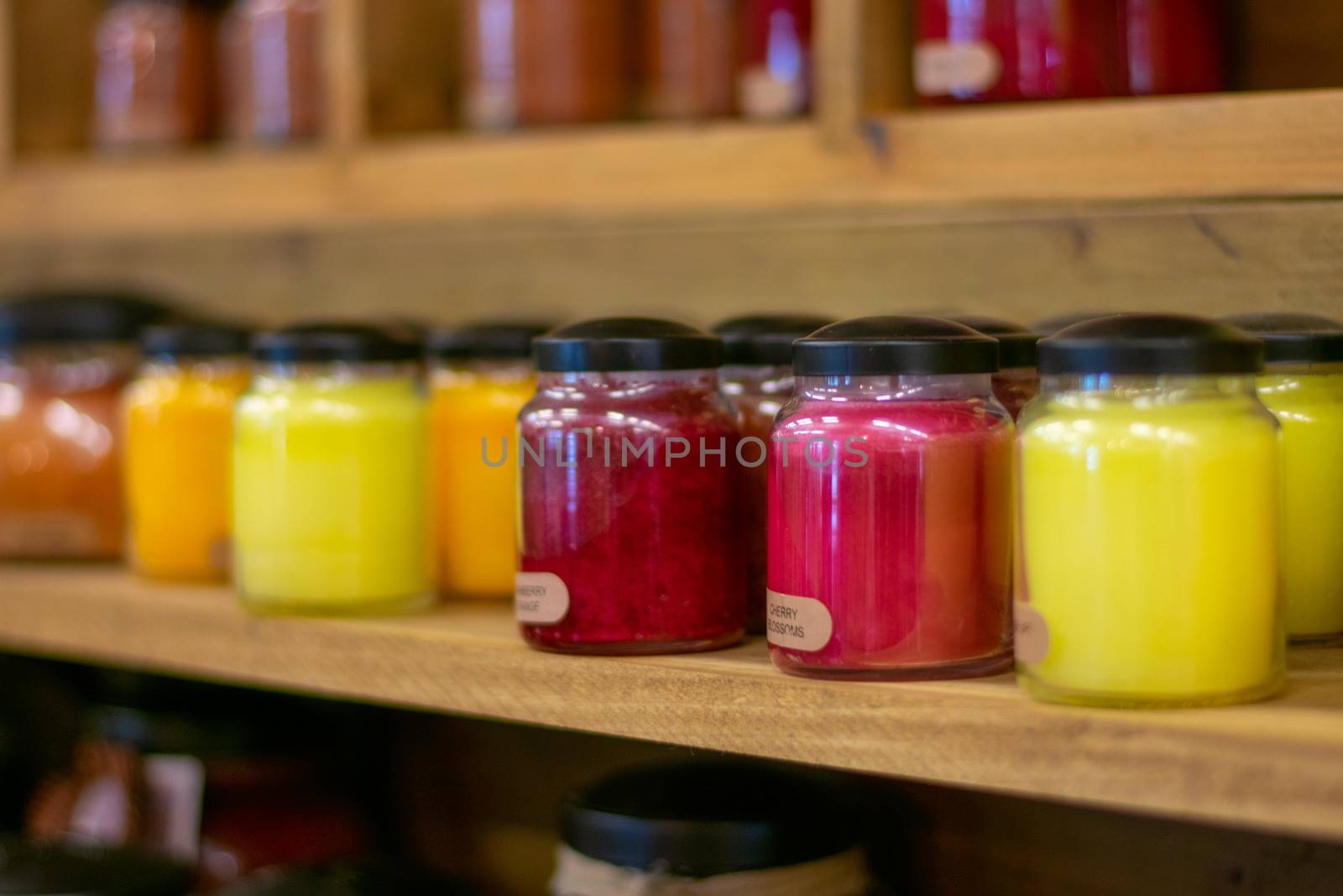 A Light Red Candle on a Shelf Full of Candles in a Farmer's Market