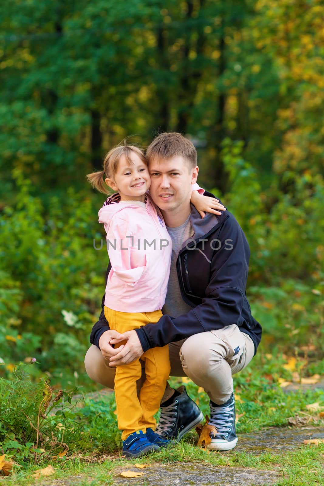 .A girl with a broken arm hugs her dad in an old park on an autumn walk.